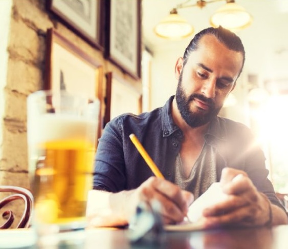 Man writing a blog while drinking a beer.