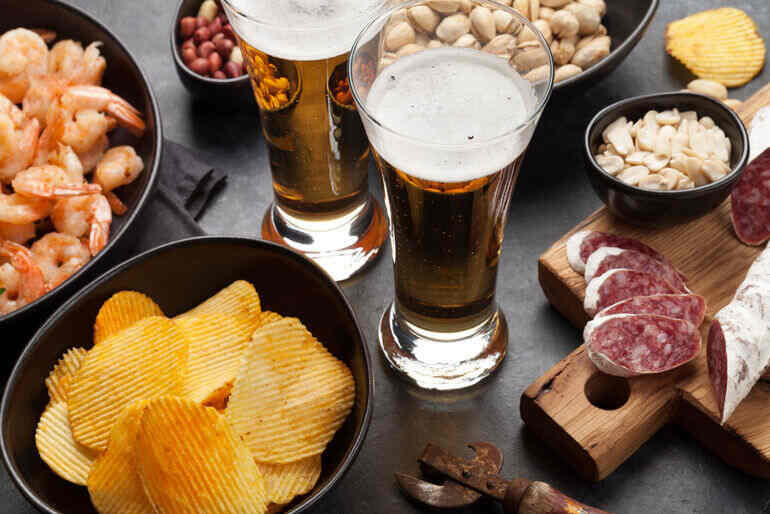 Plates of savory food with glasses of craft beer for college party