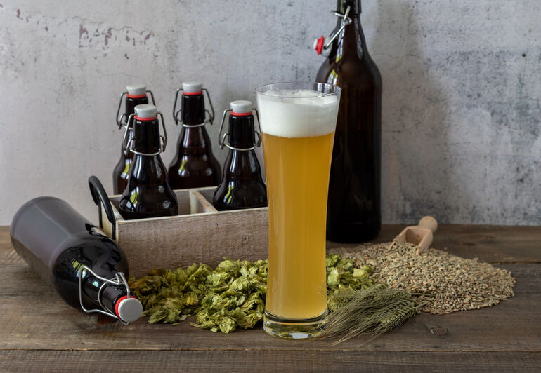 A glass of homemade beer with a record of homebrewing ingredients and bottles