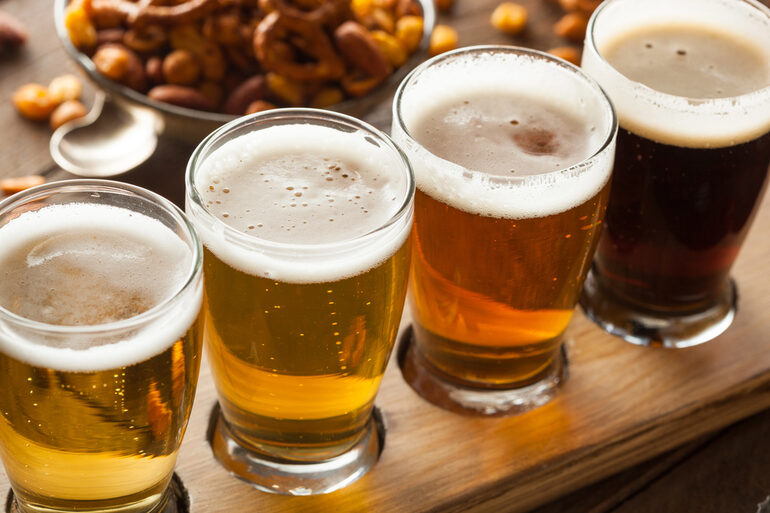 Four glasses of the world’s most expensive beers on a polished wooden surface