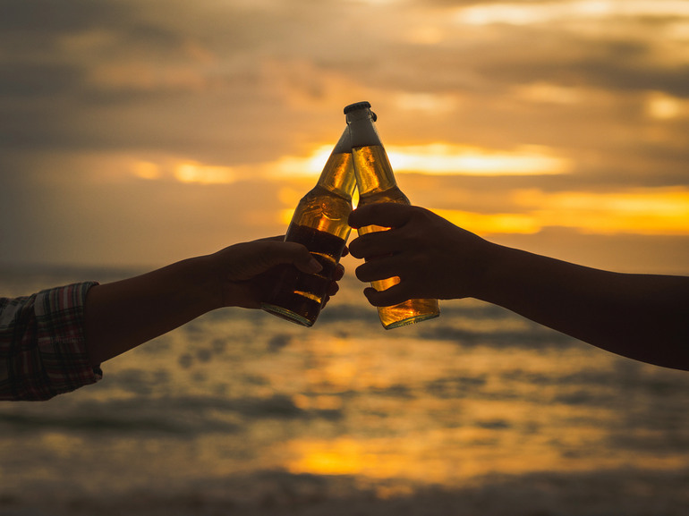 Couple holding beer bottles on their vacation to Tahiti