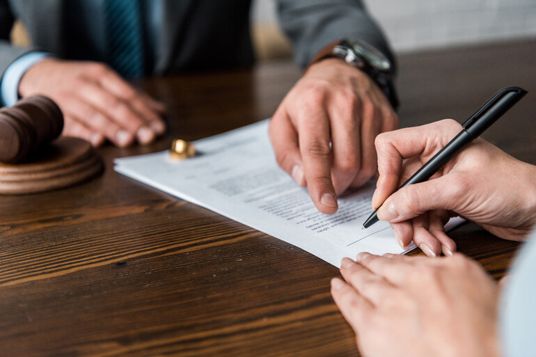 Lawyer pointing at legal papers and client signing documents