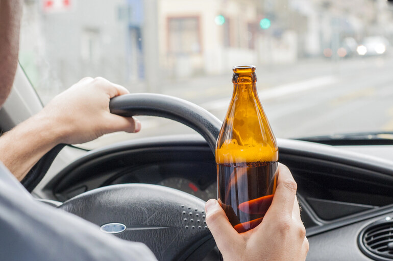 A driver holding an alcohol-free beer while driving in NYC