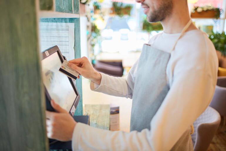 Waiter processing a contactless payment at a table, showcasing interactive display technology for efficient order management