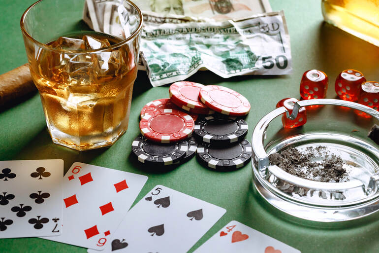 Glass of Canadian craft beer with a cigar, playing cards, and poker chips on a casino table