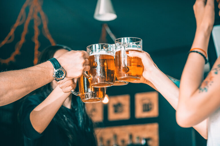 Friends toasting with beer mugs at home, showcasing a community-driven brewing experience