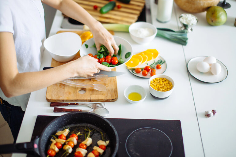 A college student making healthy salad from fresh vegetables