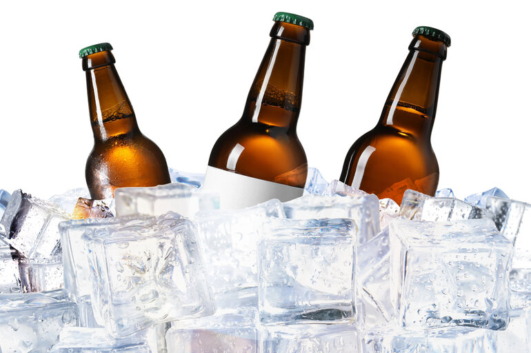 Bottles of homemade craft beer chilling on ice cubes with a clean white background