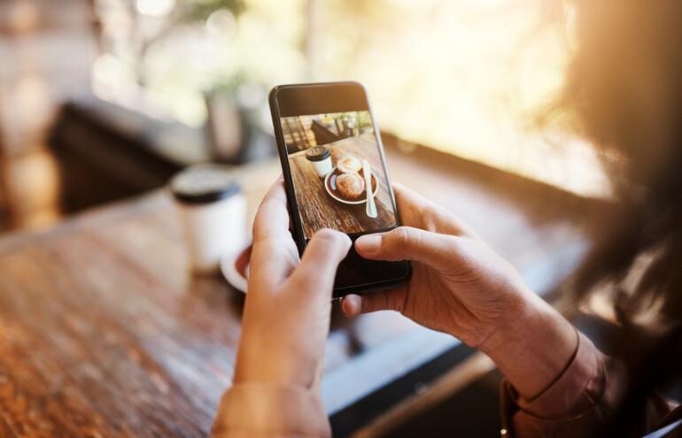 A person taking a photo at a café to share as an Instagram story