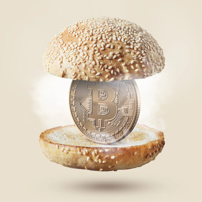 Visualization of a Bitcoin within burger buns, representing the concept of cryptocurrency revolution in the food industry