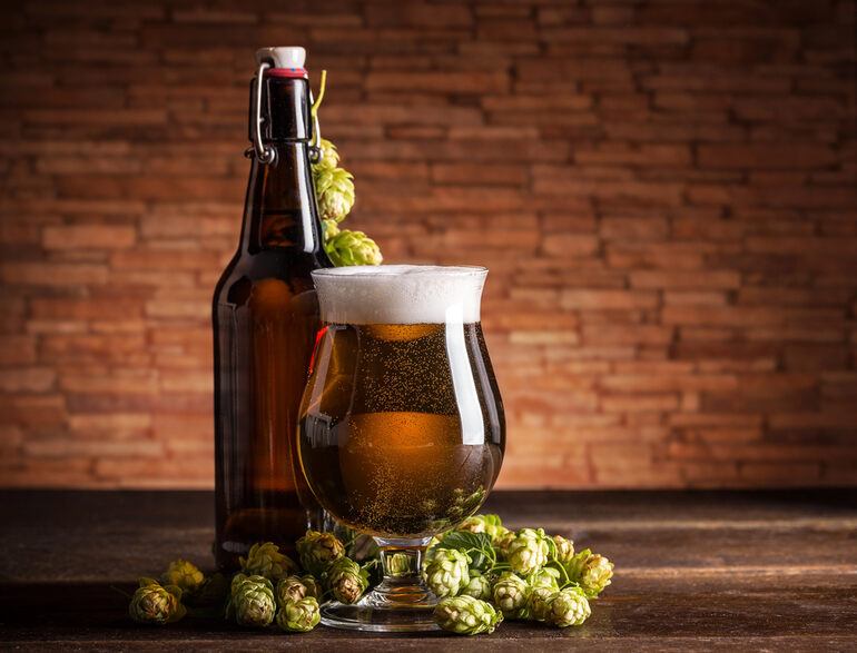CBD-infused craft beer with cannabis buds and a brown bottle on a rustic wooden table