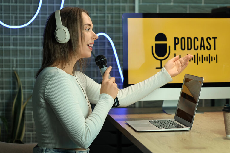 A young woman with headphones and a microphone recording a podcast