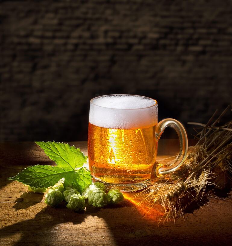 A glass of cannabis-infused homebrew surrounded by fresh green cannabis leaves