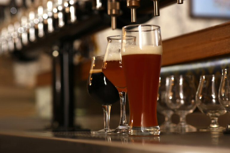 Assorted craft beers in different glasses lined up beneath tap handles at a New England brewery taproom
