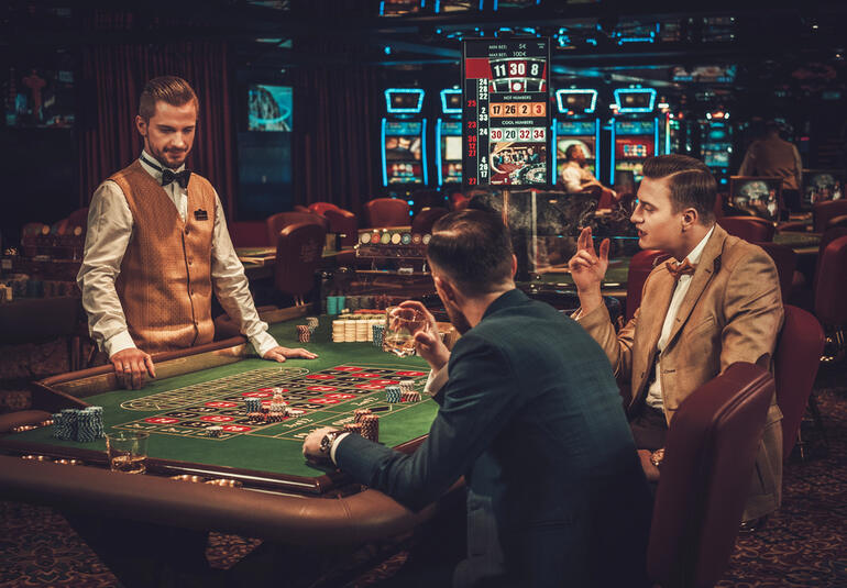 Two new players are playing roulette at a casino table with a dealer