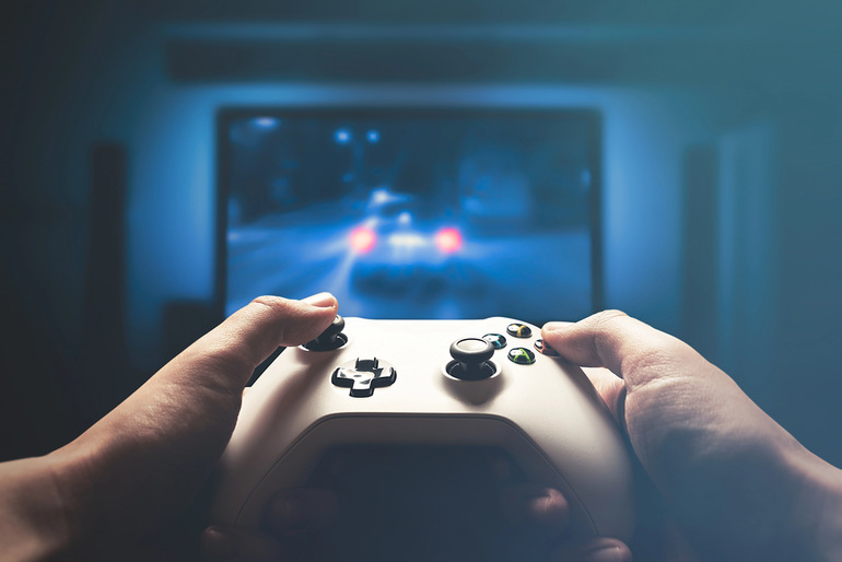 A gamer with a gaming controller in front of a blurred screen