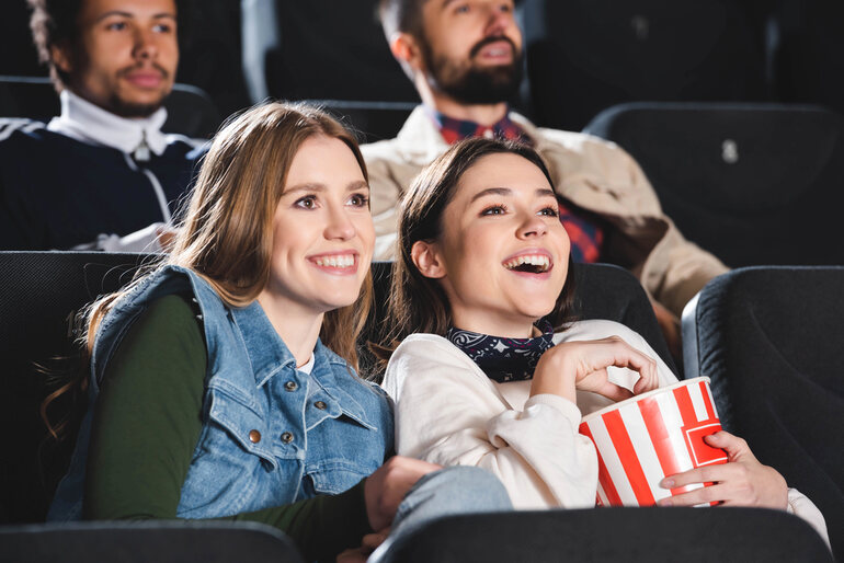Friends enjoying popcorn and watching a movie in a cinema