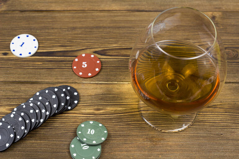 Glass of cocktail on a wooden table beside poker chips