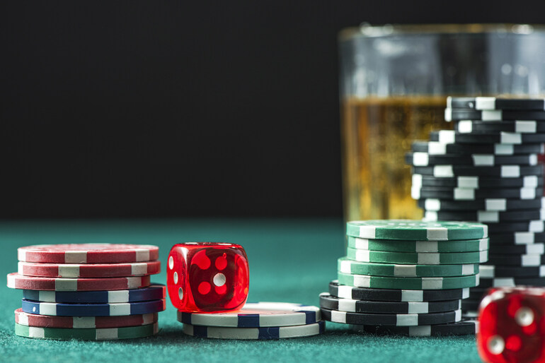 Poker chips, red dice, and a glass of homebrew on a green felt table